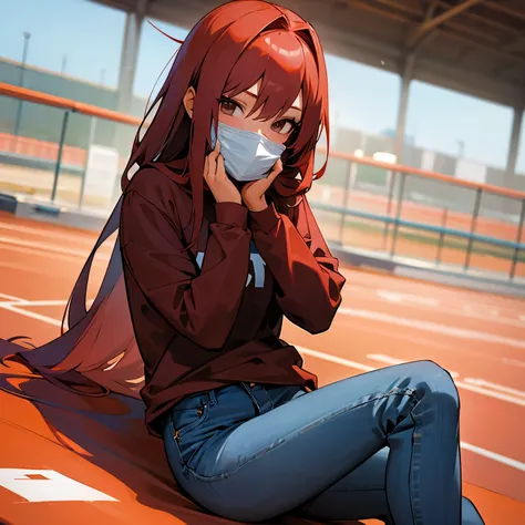 Tall red-haired girl in a red mask that covers her nose and mouth,a long-sleeved shirt underneath and a short-sleeved shirt on top and jeans sitting on a school track