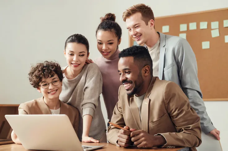 smiling group of people looking at a laptop computer together, a group of people, coworkers, diverse, people at work, group of people, bringing people together, portrait shot, professional image, diversity, in front of a computer, product introduction phot...