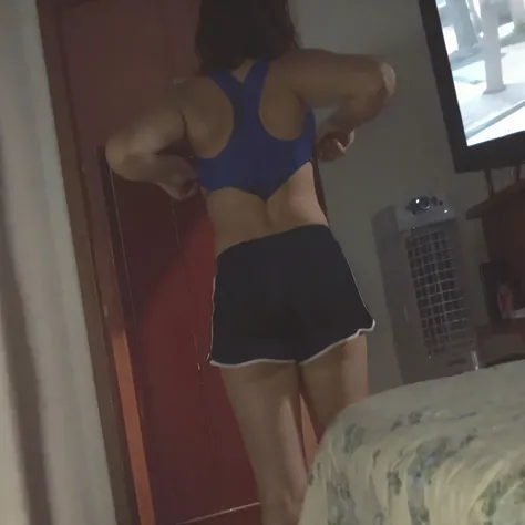 there is a woman in a blue bra top and black shorts, back - view, back - shot, seen from the back, backview, sport bra and dark blue shorts, backshot, back view!!, back shot, close-up shot from behind, shot from the back, seen from behind, in black shorts,...