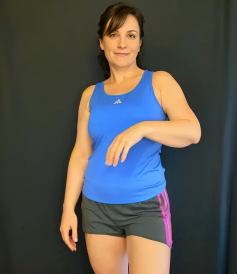 there is a woman in a blue tank top and gray shorts, short robust woman, wearing a tank top and shorts, sport bra and dark blue shorts, épaule devant pose, full body photgraph, arms to side, fit pic, half body cropping, wearing a camisole and shorts, stand...