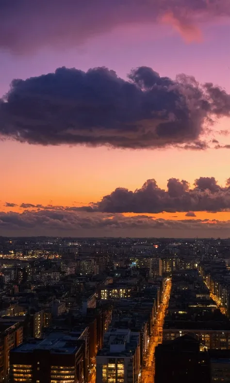 
A sky, with very noticeable clouds persisting in the evening sky. The clouds are dense and very fluffy, brightly lit by fading sunlight as the city lights begin to flicker below.