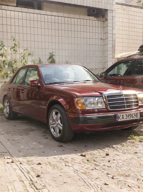 beautiful cherry colored mercedes car on the street, against the backdrop of an old house and greenery, beautiful light, bright colors, good quality, realism