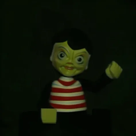 there is a small toy that is sitting in the dark, 1960s rankin bass stop motion, as a claymation character, in claymation, claymation character, still from animated horror movie, stop motion character, creepy pose, claymation style, british stopmotion, jum...