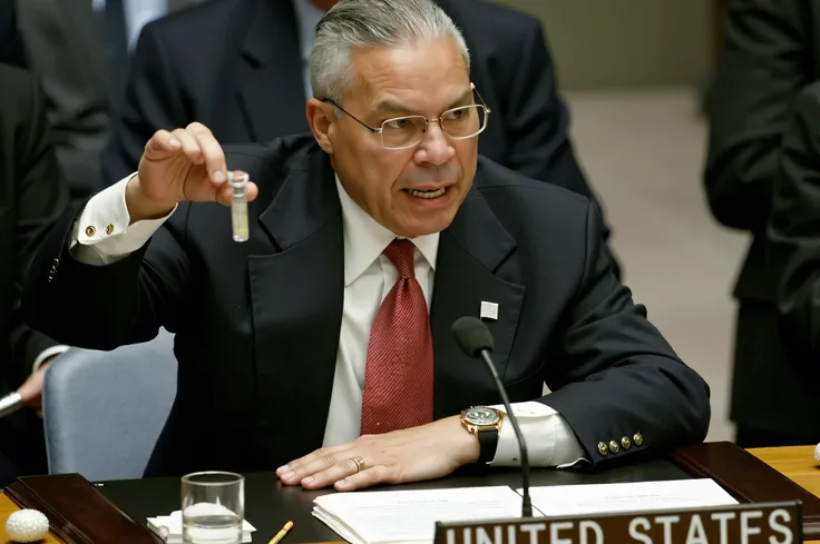  Simulate an image that represents the moment when Colin Powell ,  United States Secretary of State ,  gives his speech to the Security Council of UN .  Powell is standing in the center of the scene ,  wearing an elegant dark outfit ,  behind him there is ...