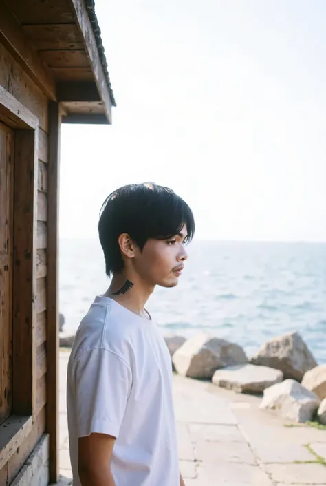 A age boy with short, dark hair, positioned on the left side of the image, is looking down and to his left. He is of East Asian ethnicity. early twenties, stands in front of an old wooden hut. He has a large tattoo on the side of his neck in the shape of a...