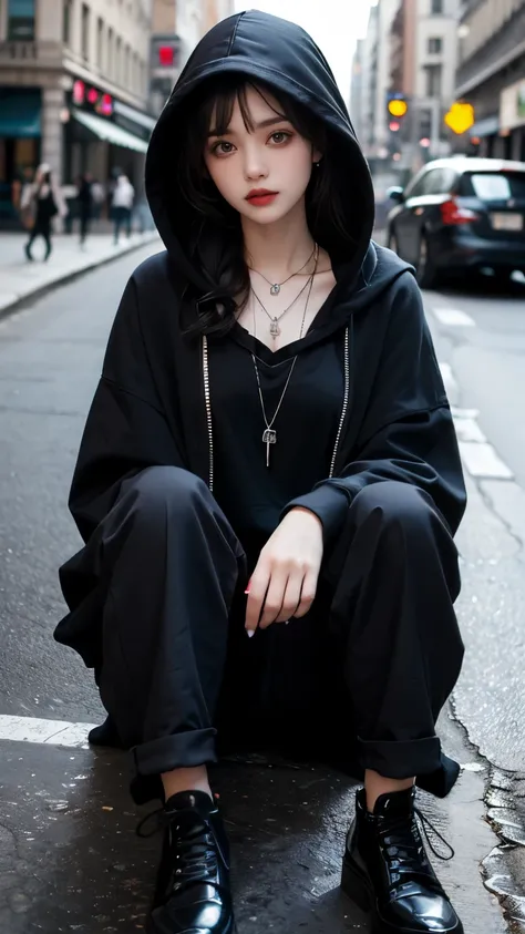sits on the street in an edgy gothic outfit. She wears a large black hood, dark hair framing her face. A black floral lace top adds elegance, with a silver pendant necklace. Her oversized black hoodie and pants feature chains, zippers, eyelets, and lace-up...