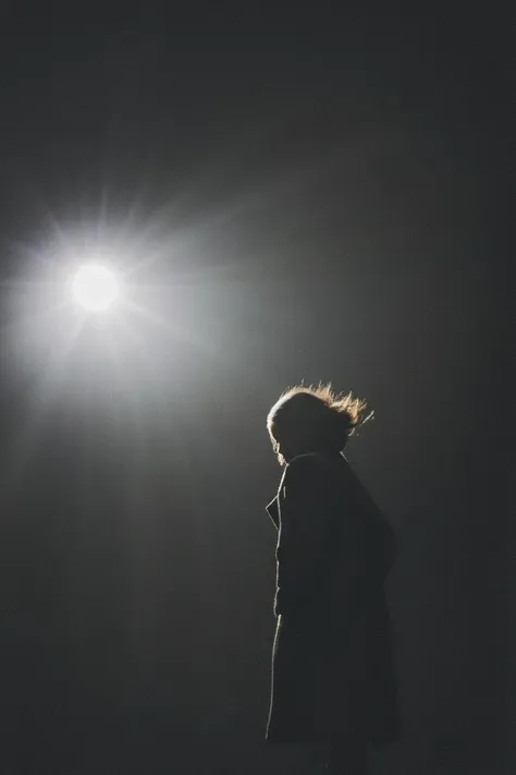 a woman standing in the dark with her hair blowing in the wind